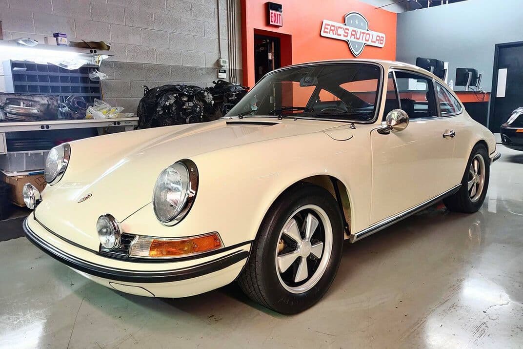 A classic air-cooled Porsche 911 in the shop beneath the Eric's Auto Lab sign